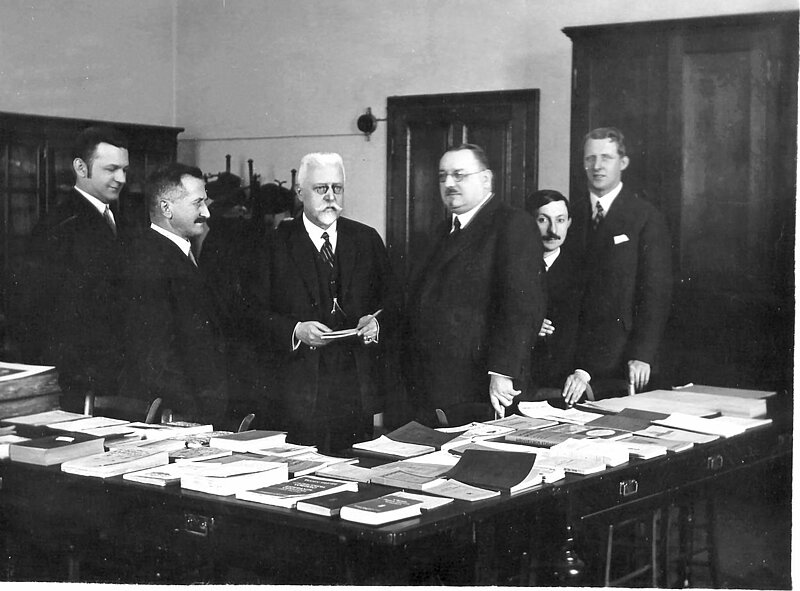 5 Männer stehend hinter einem Tisch, Hugo Steiner (2.v.l.), Johann Schober (3.v.l.) und der Generaldirektor der Nationalbibliothek, Josef Bick (4.v.l.), im Internationalen Esperanto-Museum, Wien 1931