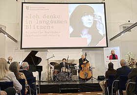 Eröffnungsrede mit Blick auf eine Bühne mit Musikinstrumenten. 