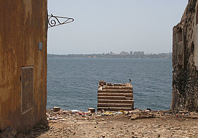 Aus einer Ruine heraus Blick auf Wasser, in der Ferne eine Stadt am anderen Ufer