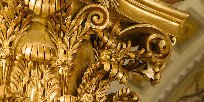 Vergoldete Stuck-Details an korinthischer Säule.