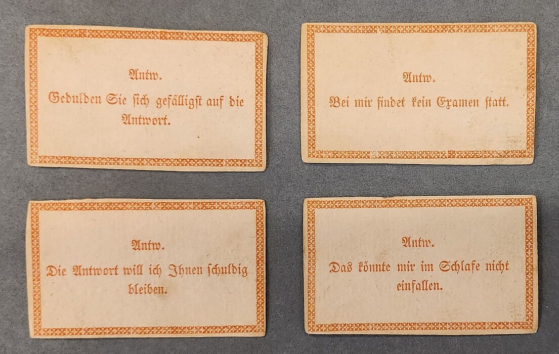 Vier Spielkarten nebeneinanderliegend mit verschiedenen Fragen darauf.