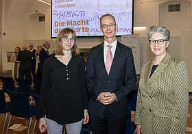 Drei Personen posieren vor Bühne.