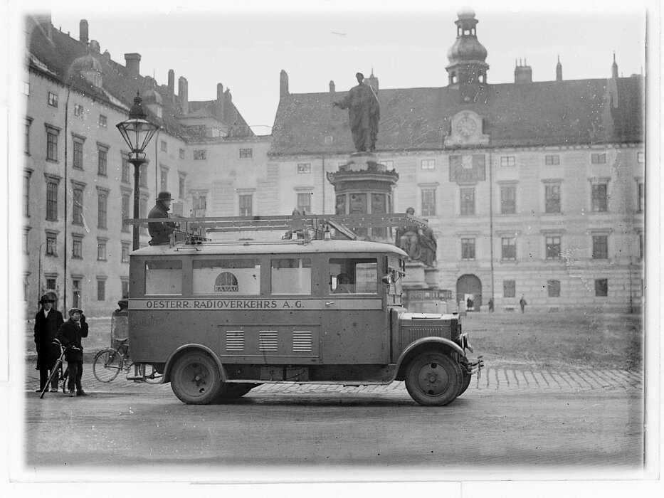 Schwarz-weißes Foto von Wagen mit Personen in Innenhof.