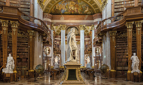 Foto von Marmorsaal mit Bücherregalen und Statuen.