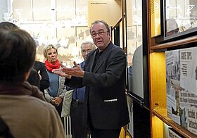 Robert Menasse hält die Hände erklärend vor sich, um ihn herum Zuhörer*innen