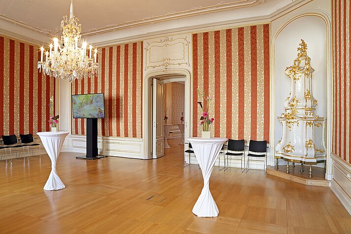 Barocker Salon mit rot-goldenen Tapeten und eingerichtet mit Stehtischen