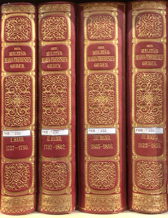 Vier prunkvoll verzierte Bücherrücken.