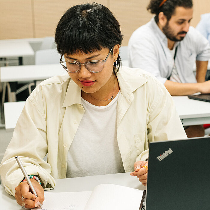 Mehrere Personen sitzen vor Laptops und machen sich Notizen 
