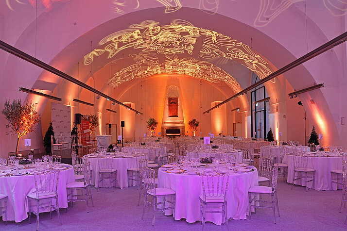 Saal mit runden Esstischen und violetter Beleuchtung 