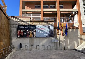 Vorplatz mit Fahrradständern, Treppe, Ausstellungsplakat vor dem Gebäude