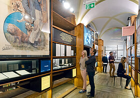 Personen in einem Museum mit alten Bücherregalen