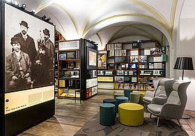 Foto von Museumsraum mit Sitzecke und deckenhohen Bücherregalen.