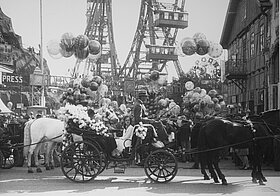 Das Riesenrad mit Luftballons und festlich geschmückten Fiakern im Vordergrund