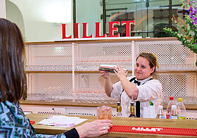Eine Person mixt Drinks an einer Bar. 