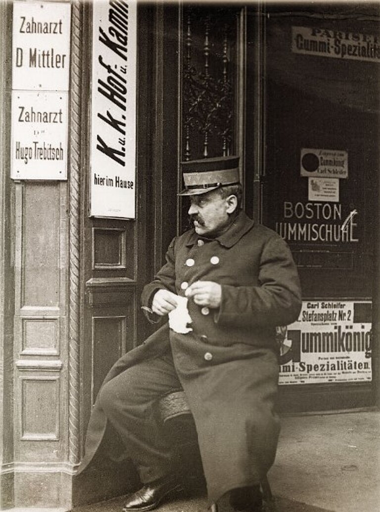 Schwarz-Weiß-Foto eines Menschen, der vor dem Eingang eines Geschäfts sitzt. 