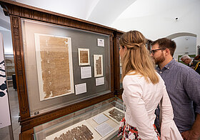 Zwei Personen sehen sich eine Vitrine im Papyrusmuseum an.