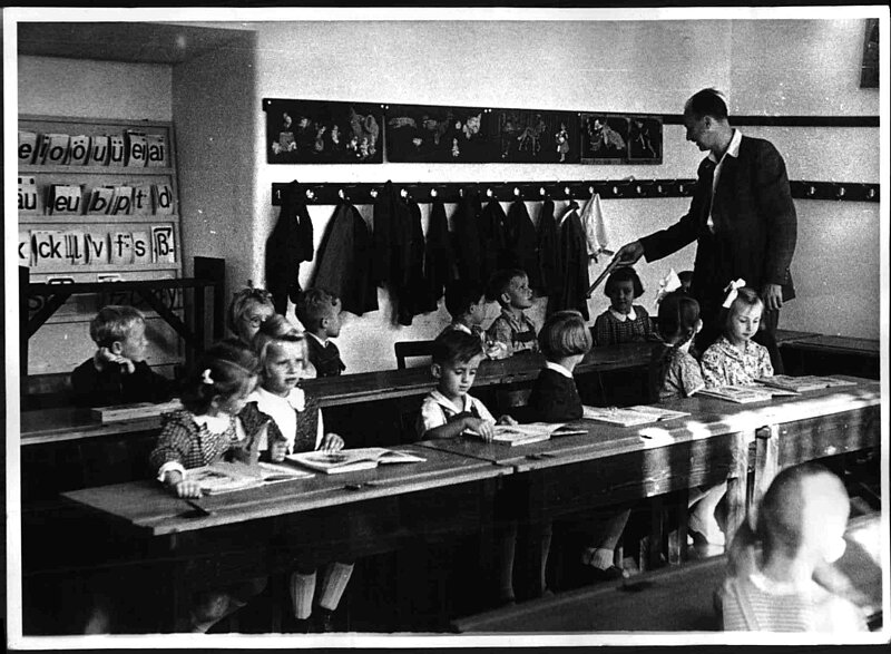 Kinder sitzen an einer Bank im Klassenzimmer, schwarz-weiß