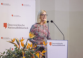 Person spricht in Mikro auf Bühne.