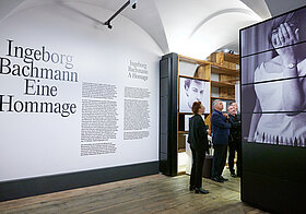 Foto vom Museumsraum mit Titel der Ausstellung an der Wand und Regalen.