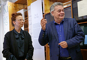 Zwei Personen unterhalten sich zwischen Museumsregalen.