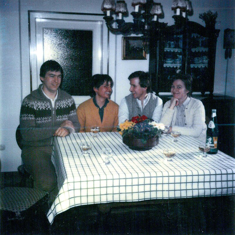 Zwei Männer und zwei Frauen sitzen an einem Tisch mit karierter Tischdecke