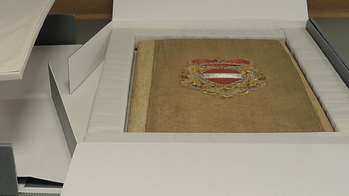 Die Erbhuldigungsadresse die in einem kunstvoll verzierten Textileinband gebunden ist, wird in einer archivbeständigen Wellkartonbox mit besonderer Auskleidung aufbewahrt.