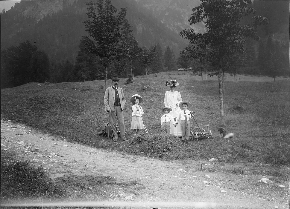 Schwarz-weißes Foto von zwei Erwachsenen und drei Kindern auf einer Wiese.