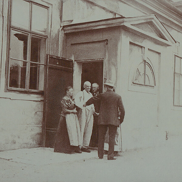 Ausschnitt von einem schwarz-weißen Foto  von vier Personen, die vor einem Haus stehen