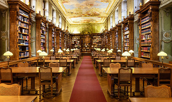 Barocker Lesesaal mit alten Bücherregalen, himmischem Deckenfresko und rotem Teppich