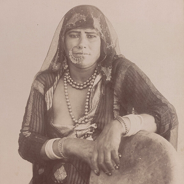 Alte schwarz-weiße Fotografie, eine Frau mit Nasenring und Kopftuch sitzt für ein Portrait
