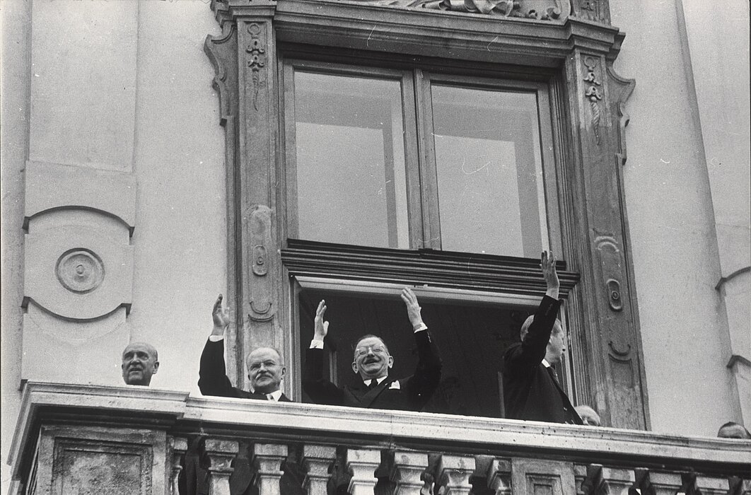 Schwarz-weißes Foto von Personen, die von Balkon winken.