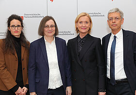 Vier Personen posieren nebeneinander für ein Foto. 