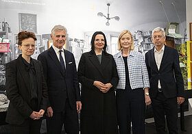Vier Personen vor Fotowand.