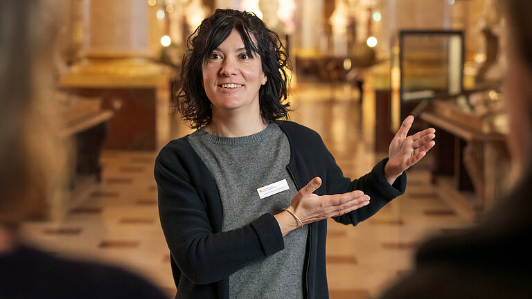 Foto von Person in Marmorsaal die "Willkommen" in Gebärdensprache zeigt.
