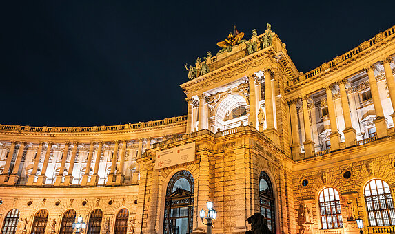 Foto von U-förmigem, altem Gebäude bei Nacht, beleuchtet.