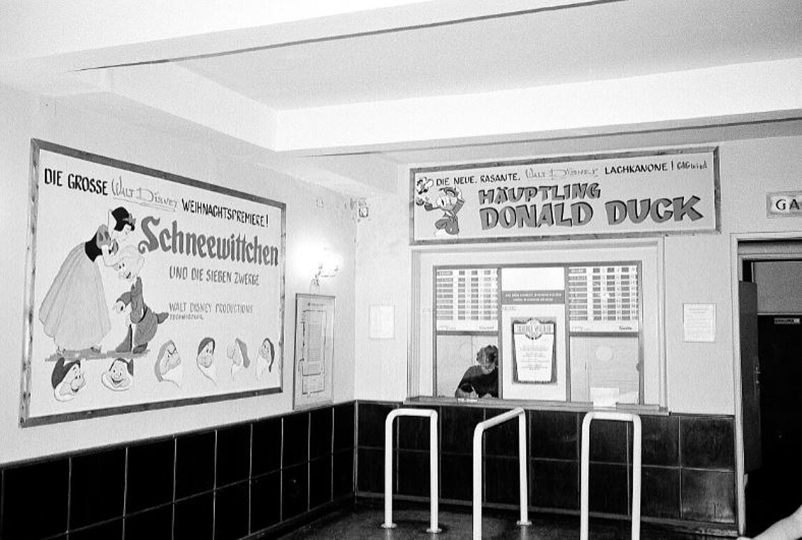 Schwarz-weißes Foto eines Kino-Kassenbereichs mit Filmpostern