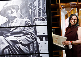 Person steht lächelnd im Literaturmuseum. Links im Vordergrund ein Foto von Stefan Zweig.