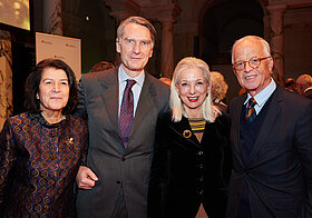 Foto von vier Personen in eleganter Kleidung.