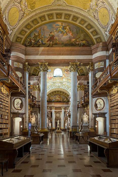 Foto von Museumsraum mit Statuen, Deckenfresko und Bücherregalen.