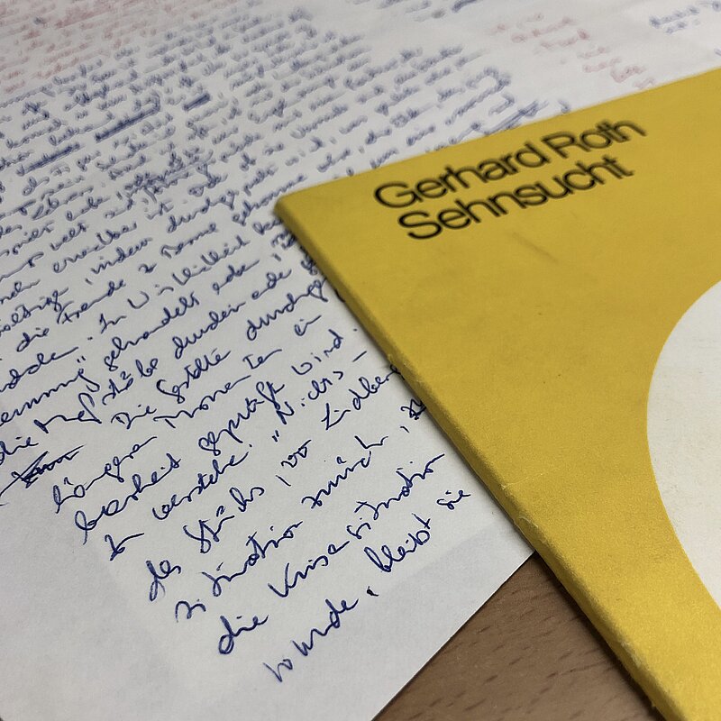 Handgeschriebene Notizen und ein gelbes Buchcover mit der Aufschrift "Gerhard Roth: Sehnsucht"