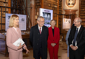 Vier Personen stehen vor Vitrinen in Museum.