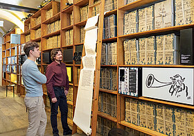 Personen in einem Museum mit alten Bücherregalen