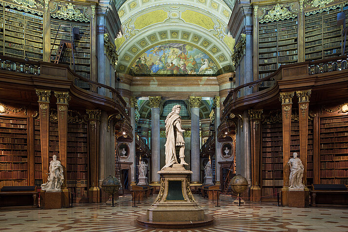 Statue von Karl VI. im Zentrum eines barocken Bibliothekssaal