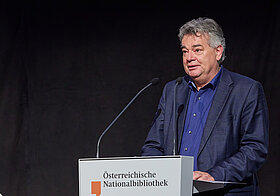 Person im Anzug am Rednerpult.