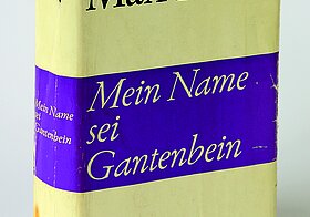 Ein Buch mit leicht beschädigtem Papierumschlag. Auf dem Cover sind nur Autor, Titel und Verlag geschrieben.