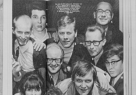 Eine Gruppe von Leuten lehnt sich aus einem Fenster. Auf der Reproduktion einer Magazinseite sind diese Personen nummeriert und mit Namen verzeichnet.