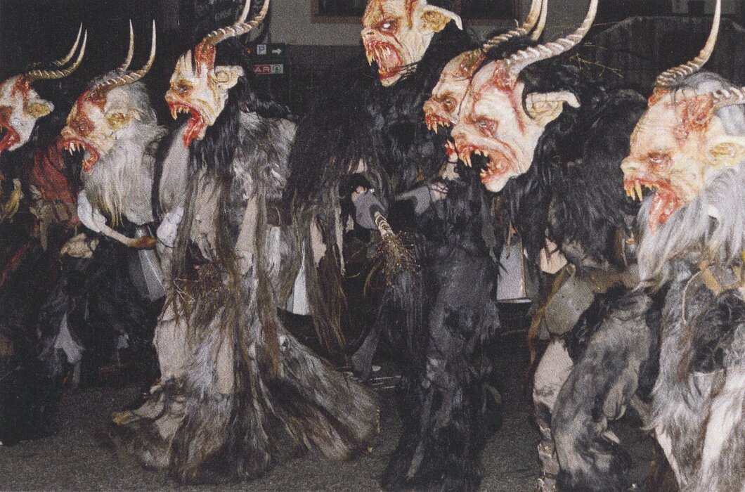 Foto von Personen in scheußlichen Kostümen mit Fell, Hörnern und großen Zähnen.