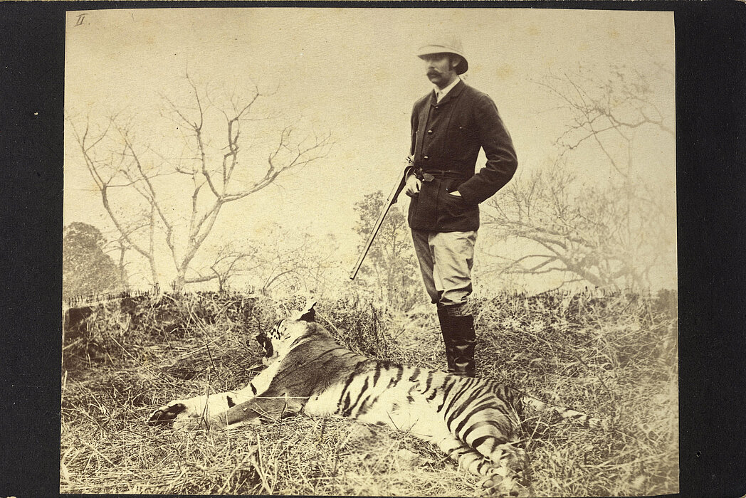 Schwarz-weißes Foto von Person mit Waffe allein neben totem Tiger.