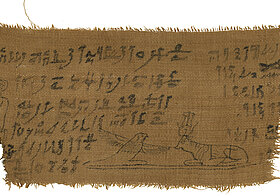 Stoffstück mit ausgefransten Kanten, Hieroglyphen und Zeichnungen von einem Vogel und einer Kuh.