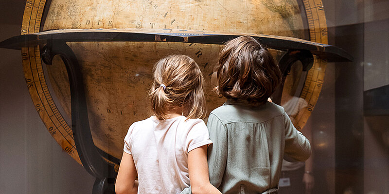 Zwei Kinder schauen einen riesigen Globus an.